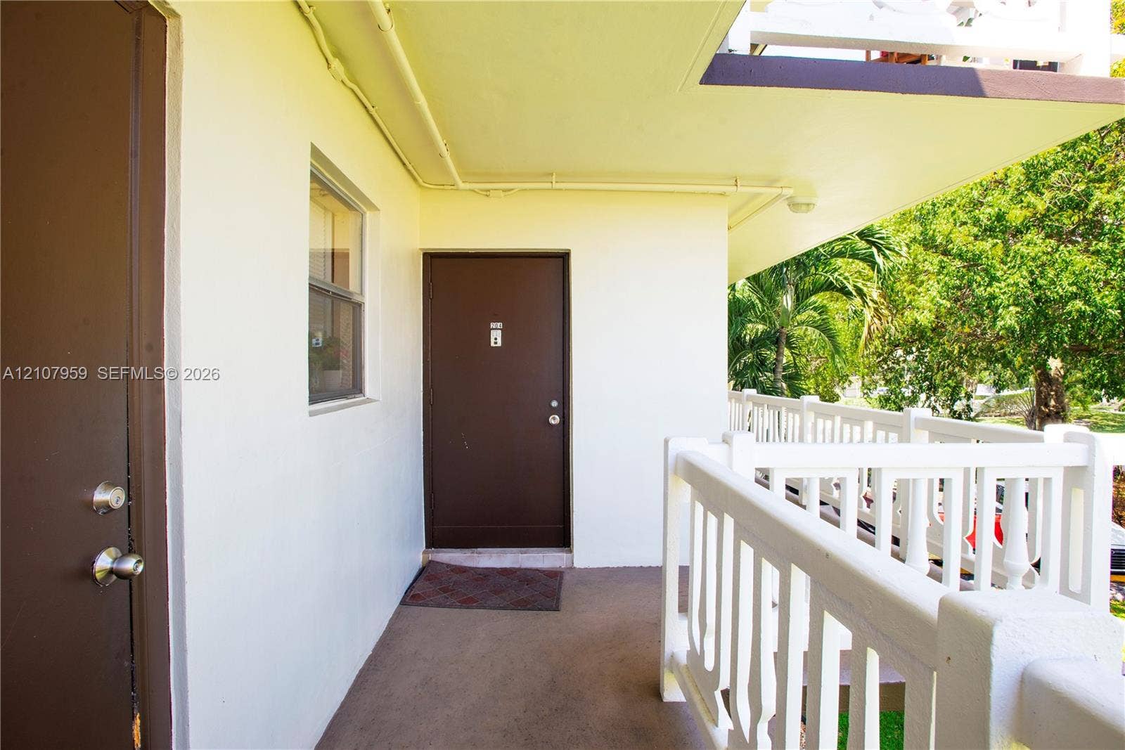 4200 Crystal Lake Drive, #204, Deerfield Beach, Deerfield Beach, FL 33064 Covered exterior walkway featuring a concrete floor, solid-core doors with metallic hardware, and a white balustrade railing
