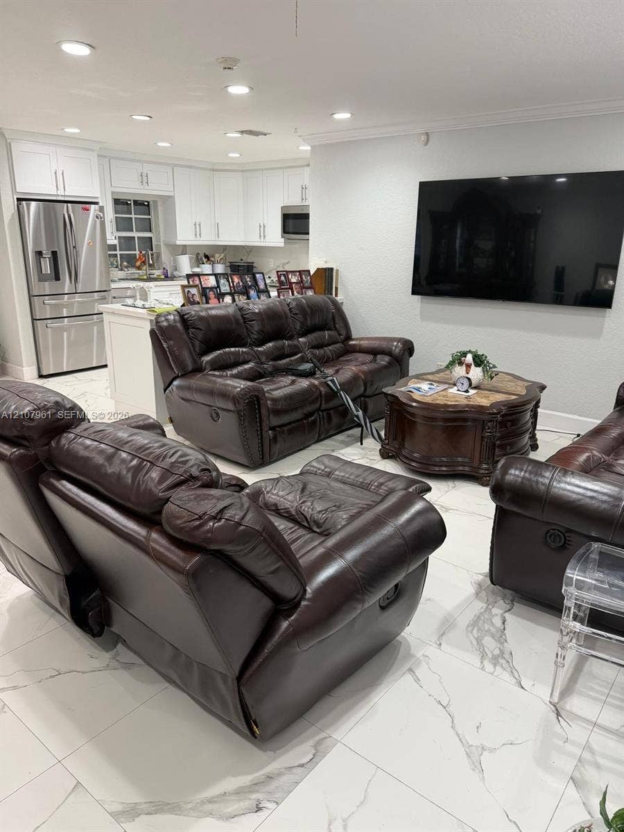 Open floor plan featuring white cabinetry, stone-finish tile flooring, recessed ceiling lighting, and stainless steel appliances