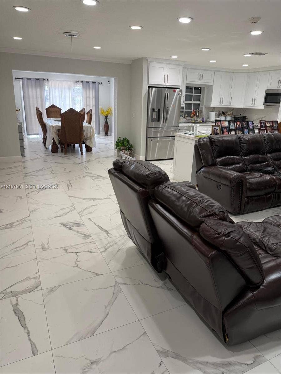 Large-format white tile flooring with grey veining, recessed lighting, white cabinetry, and stainless-steel appliances