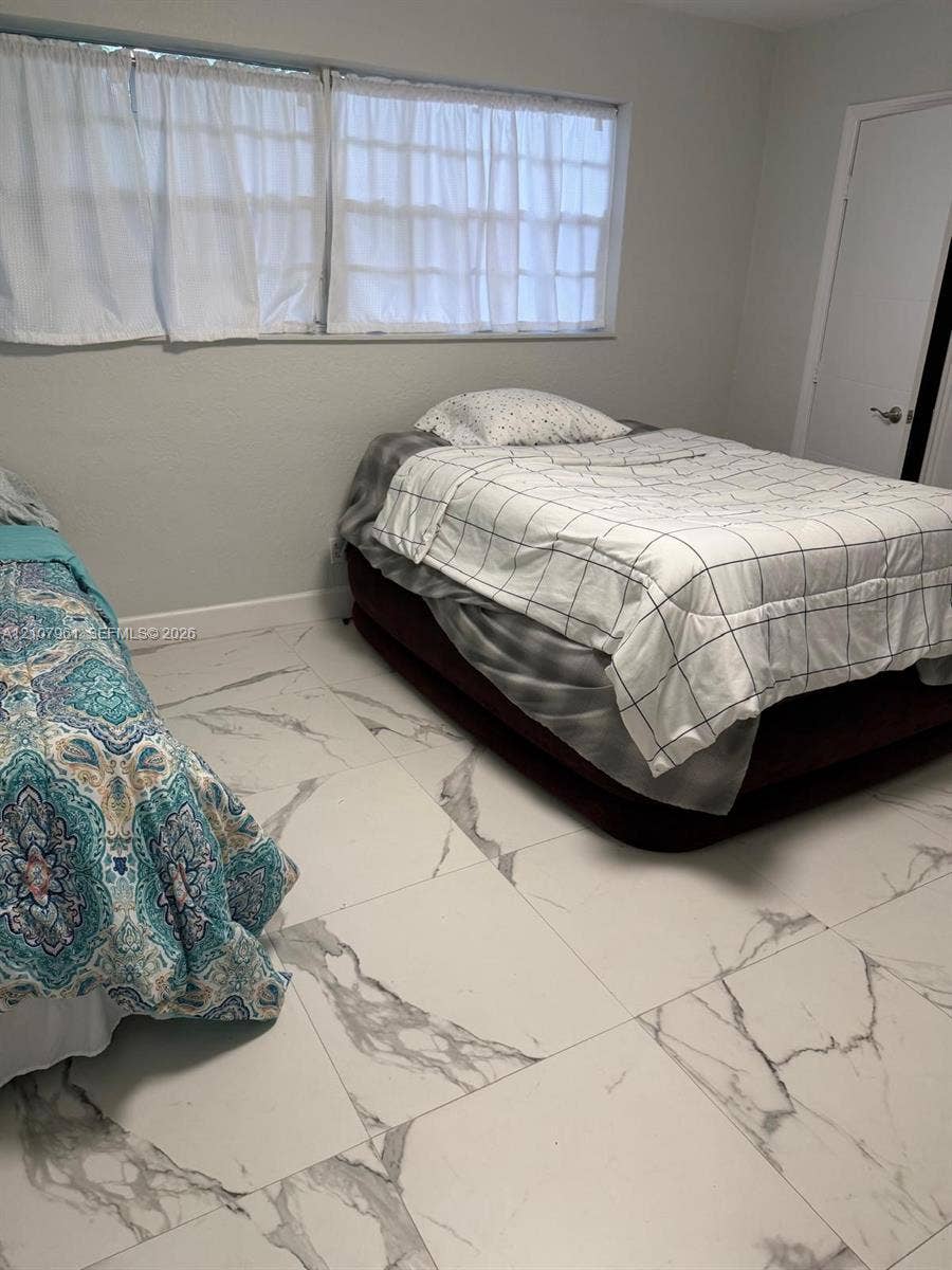 Large-format tile flooring with a stone-inspired pattern, multi-pane window, and interior door with brushed metal hardware