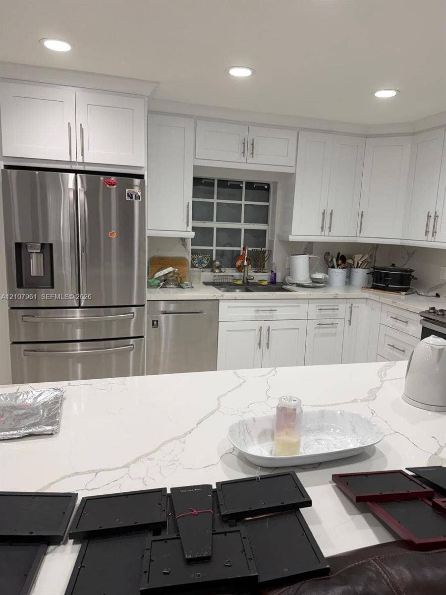Kitchen featuring white shaker-style cabinetry, quartz countertops with veining, recessed lighting, and stainless steel appliances