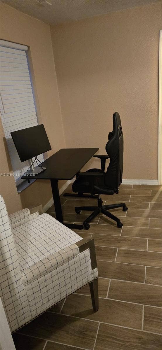 Room featuring wood-finish tile flooring and a window with horizontal blinds