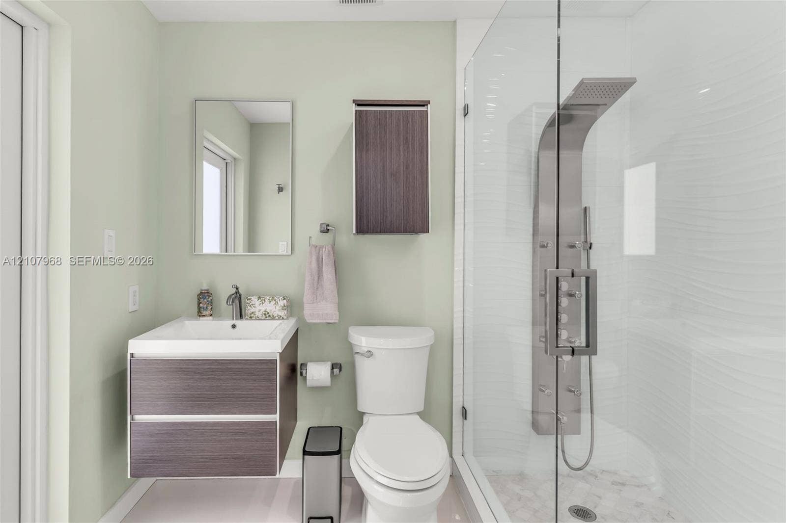 10841 SW 126th Street, Miami, FL 33176 Floating vanity featuring a square vessel sink, integrated wood-finish cabinetry, shower enclosure with a stainless steel rainfall panel system, and a wall-mounted wood-finish storage cabinet