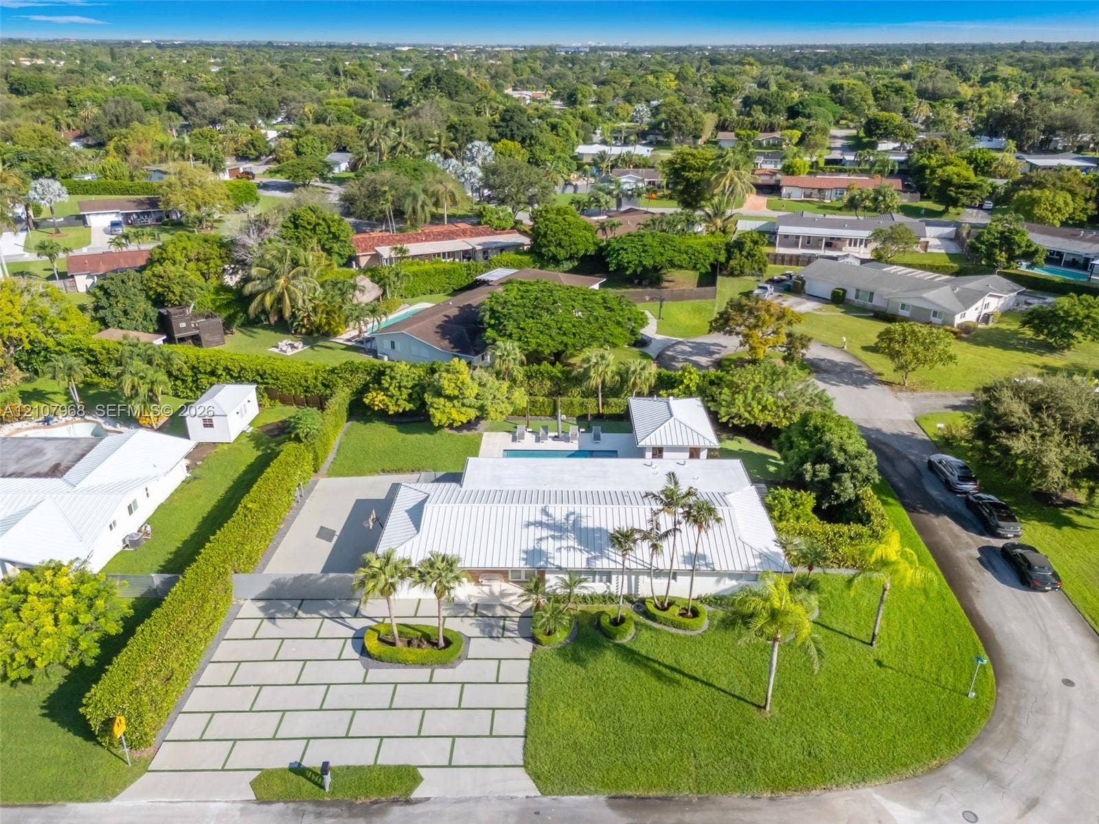 10841 SW 126th Street, Miami, FL 33176 Aerial perspective featuring a metal roof, paved geometric driveway, swimming pool, detached structure, and mature landscaping