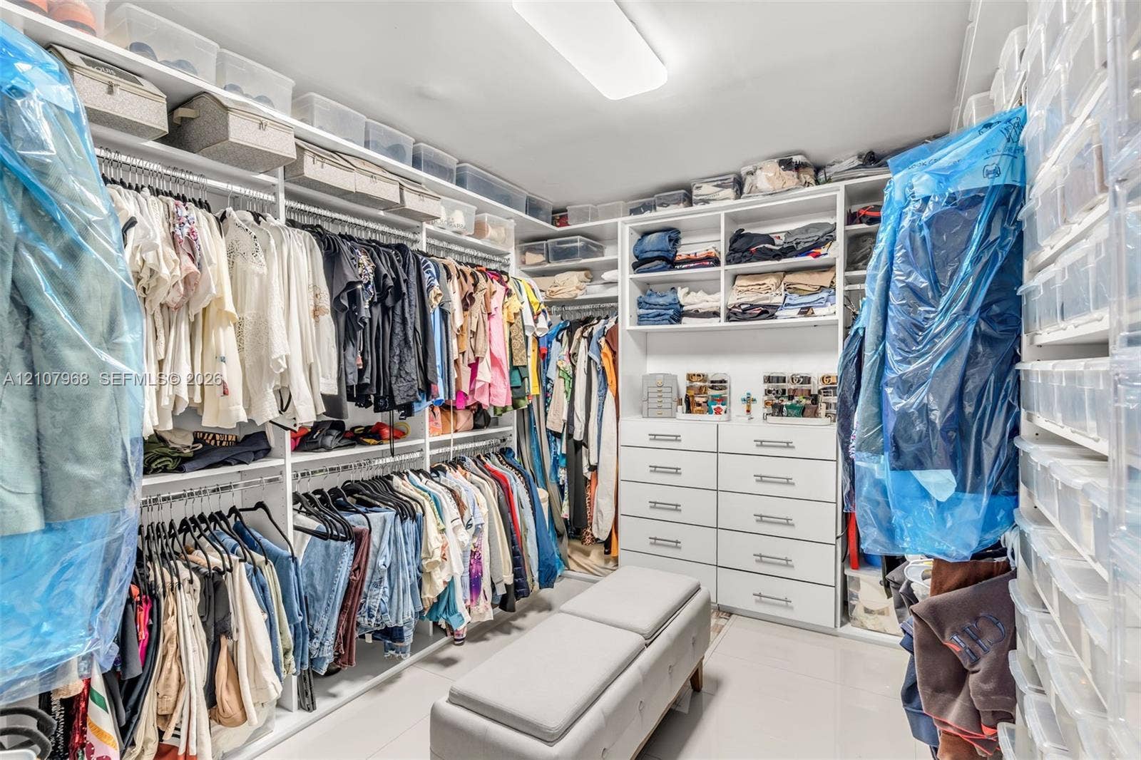 10841 SW 126th Street, Miami, FL 33176 Custom walk-in closet featuring extensive white built-in shelving, integrated dresser drawers with hardware pulls, and overhead lighting