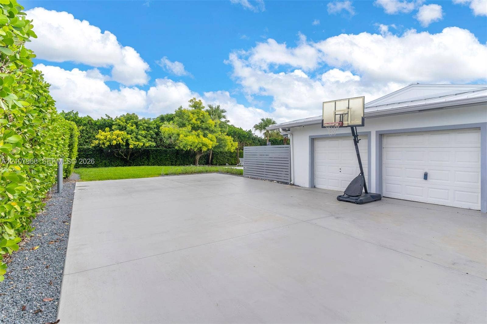 10841 SW 126th Street, Miami, FL 33176 Concrete driveway with two-car garage, manicured lawn, and perimeter privacy hedges