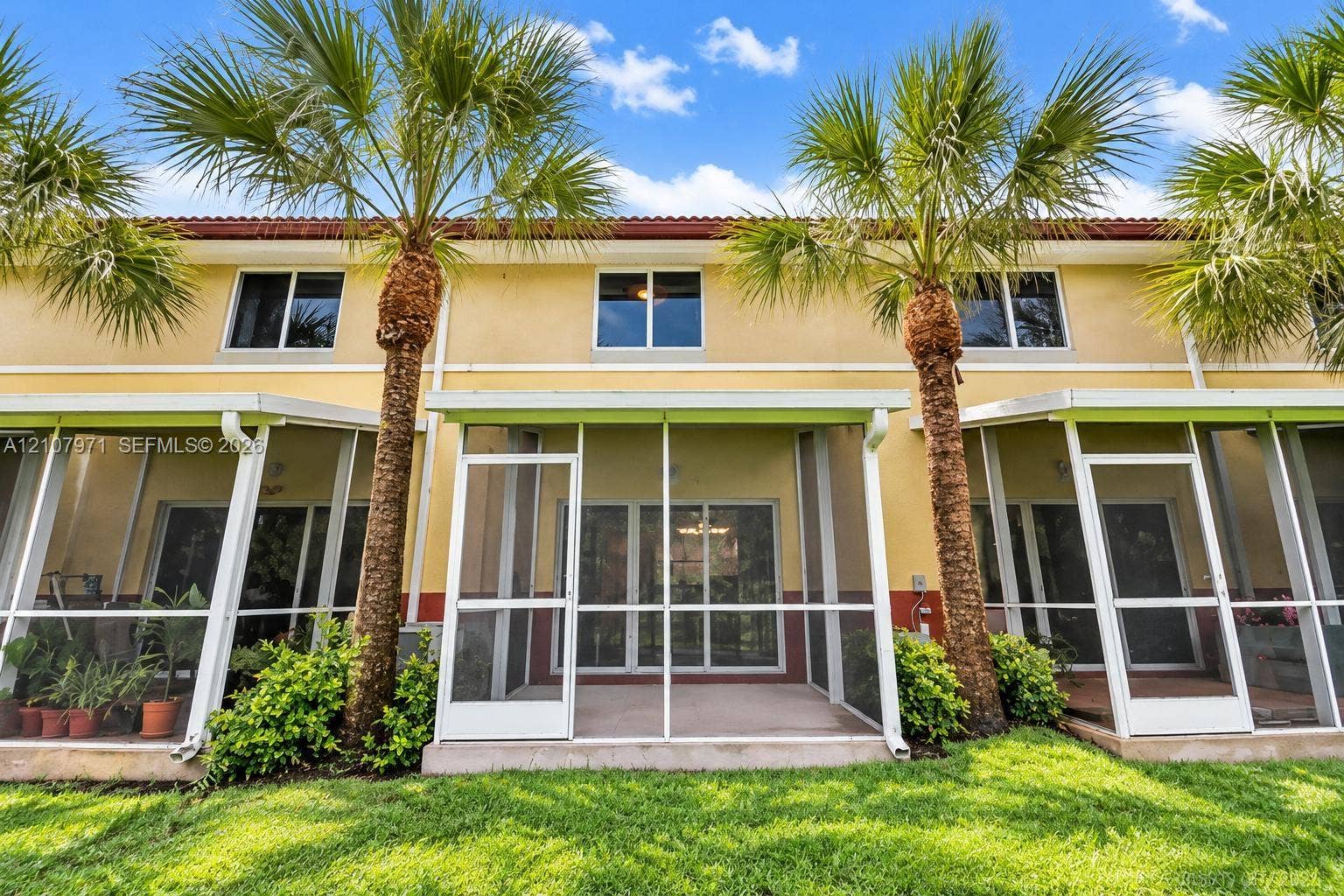 4921 SW 66th Terrace, #4921, Davie, Davie, FL 33314 Stucco exterior featuring multiple screened-in lanais, concrete patio flooring, and mature palm trees