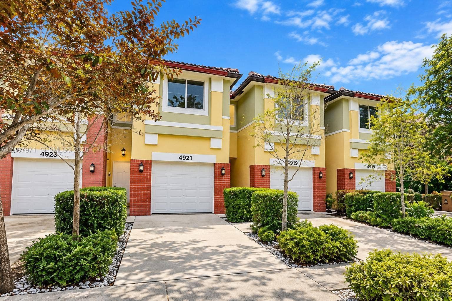 4921 SW 66th Terrace, #4921, Davie, Davie, FL 33314 Multi-unit residential exterior featuring a multi-toned stucco facade, brick lower-level detailing, multi-pane windows, and individual garage access