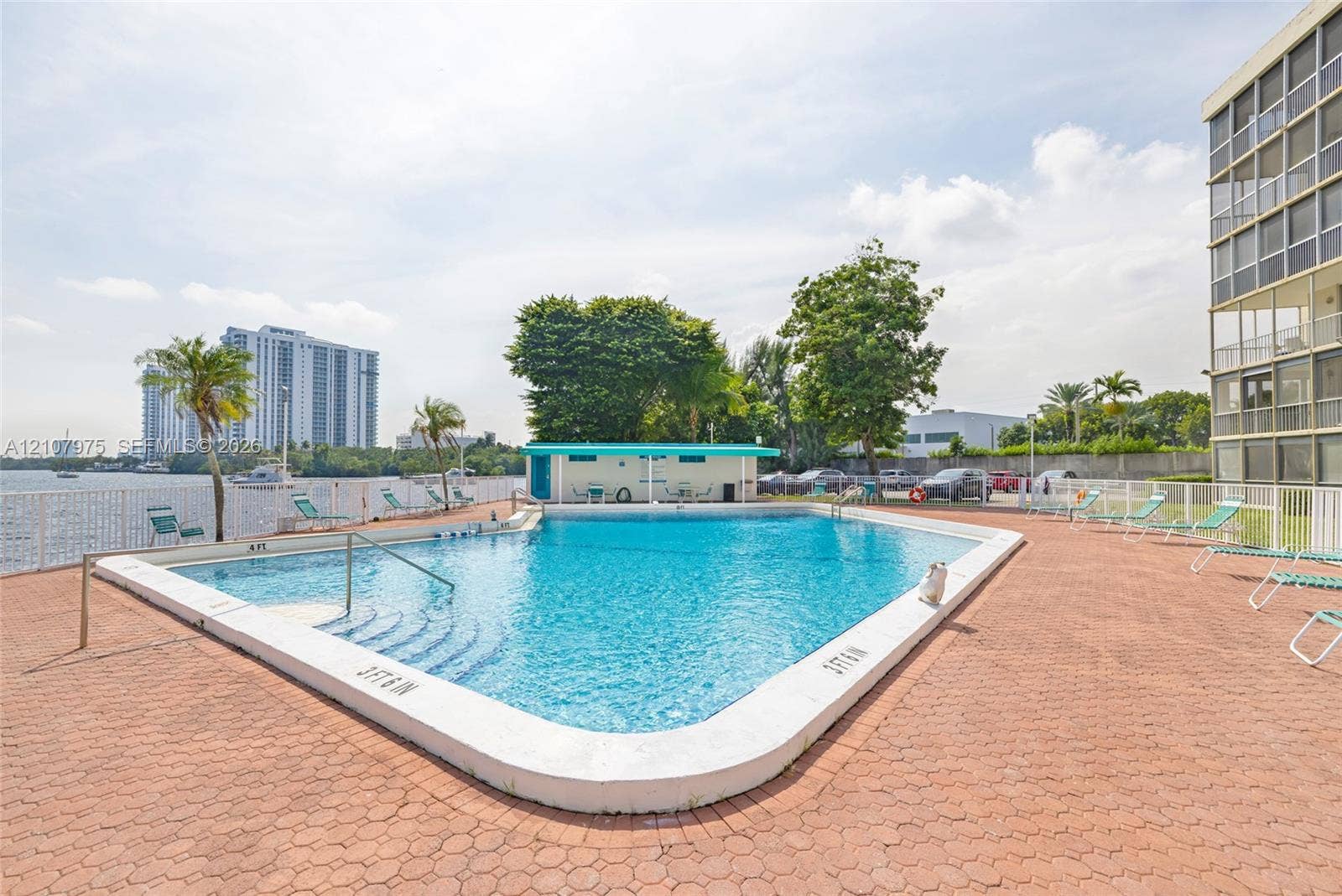 2910 Point East Drive, #M108, Aventura, FL 33160 Outdoor swimming pool featuring a brick paver deck, metal perimeter fencing, and an on-site cabana