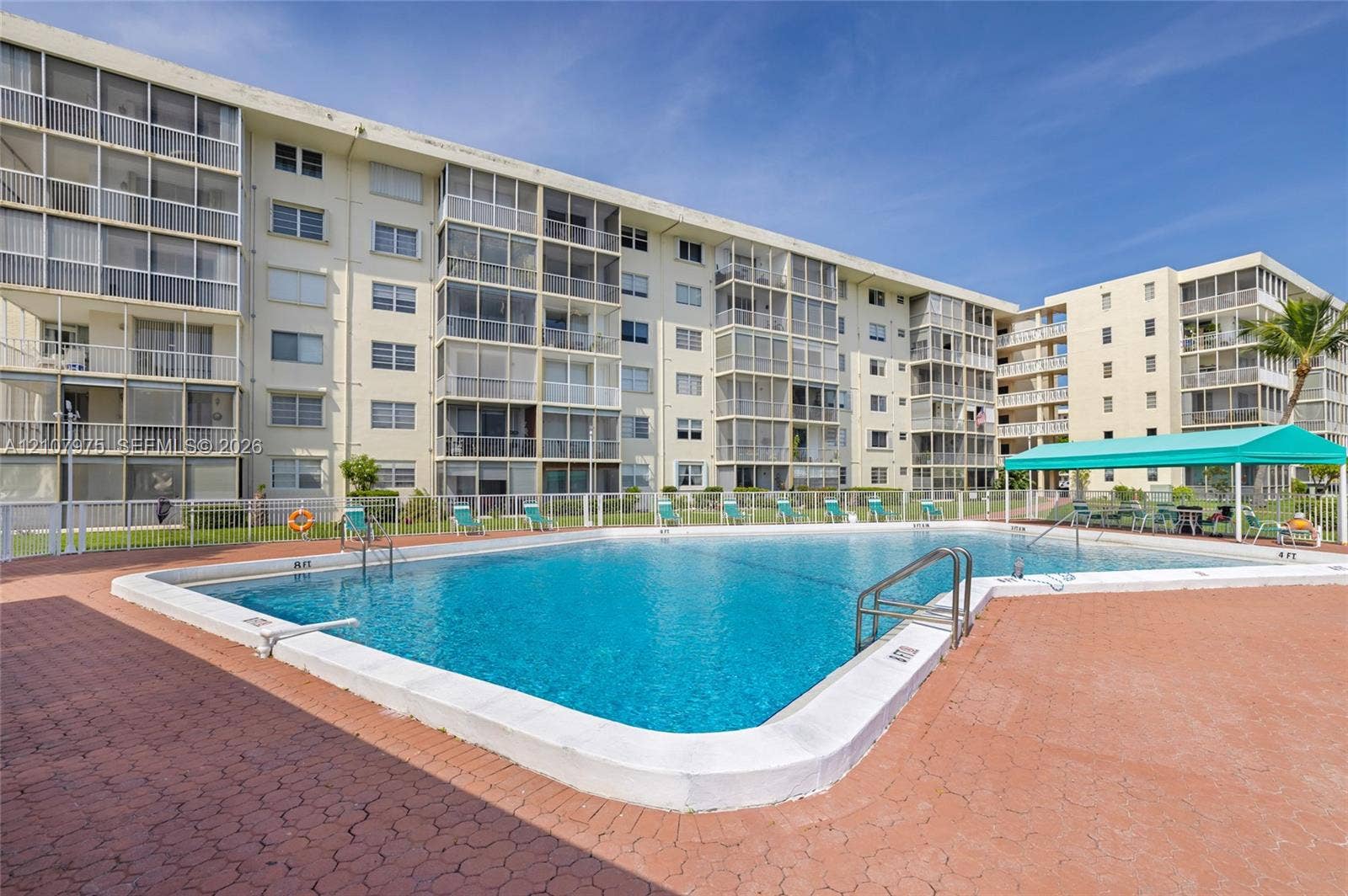 2910 Point East Drive, #M108, Aventura, FL 33160 In-ground swimming pool featuring a concrete deck, metal pool ladder, and shaded canopy area