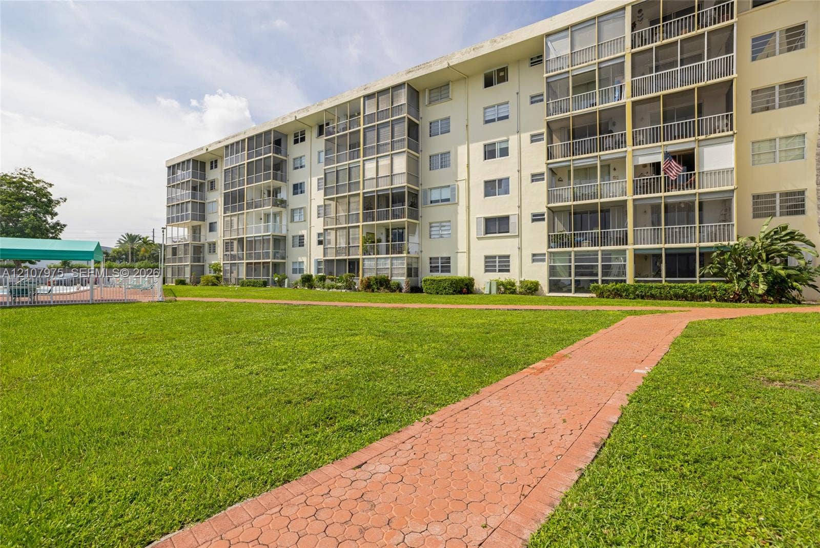 2910 Point East Drive, #M108, Aventura, FL 33160 Multi-story building featuring screened balconies, landscaped grounds, and paved walkways