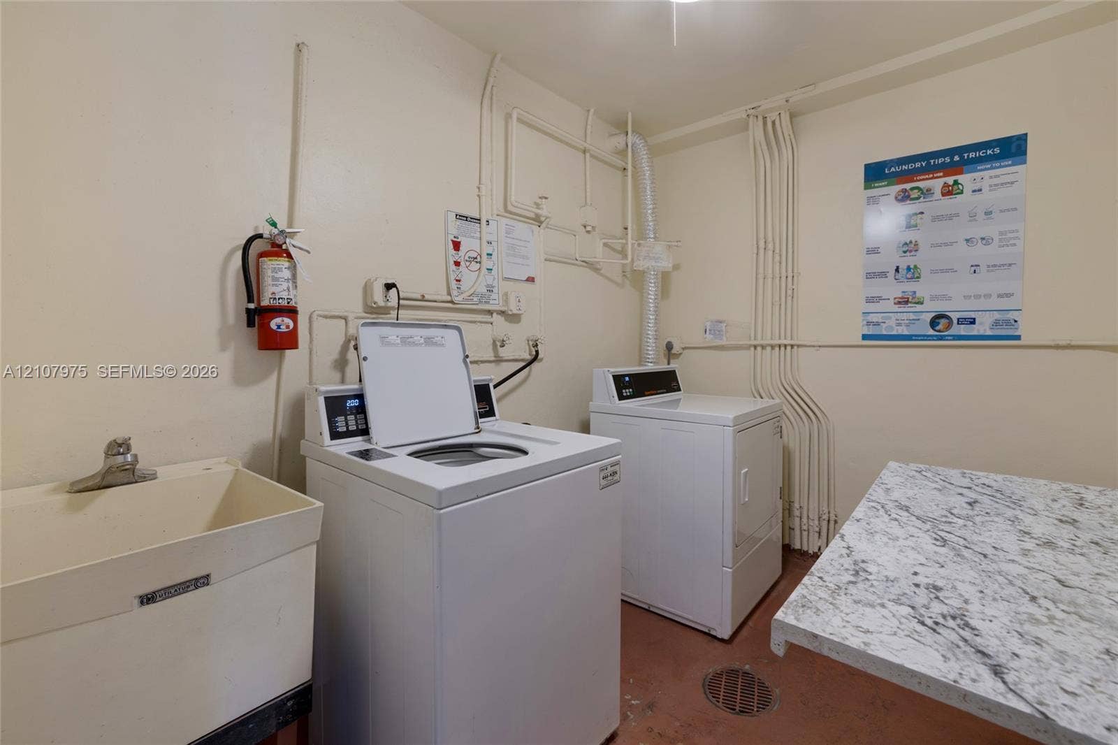 2910 Point East Drive, #M108, Aventura, FL 33160 Laundry area featuring a utility sink with a chrome faucet, stone-finish countertop, and dedicated hookups for laundry appliances