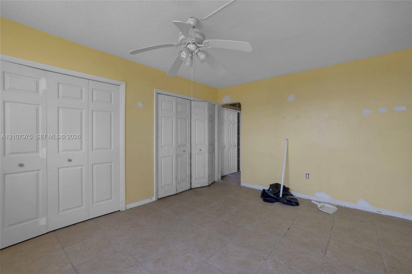 2910 Point East Drive, #M108, Aventura, FL 33160 Room featuring ceramic tile flooring, a white ceiling fan with integrated lighting, and two sets of bi-fold closet doors