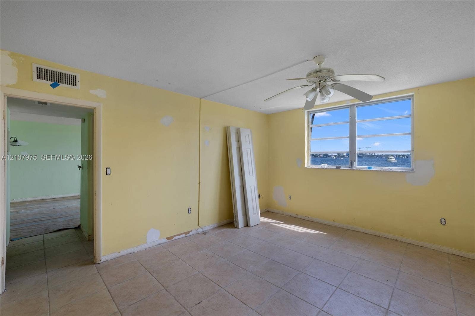 2910 Point East Drive, #M108, Aventura, FL 33160 Interior space featuring large-format ceramic tile flooring, a ceiling fan with integrated lighting, and a multi-pane horizontal window