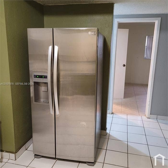 5100 SW 41st Street, #101, Hollywood, Hollywood, FL 33023 Stainless steel side-by-side refrigerator with external water and ice dispenser, white ceramic tile flooring, and solid-core interior doors