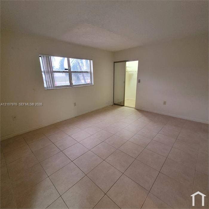 5100 SW 41st Street, #101, Hollywood, Hollywood, FL 33023 Neutral-toned tile flooring, large window with horizontal blinds, and closet with sliding mirrored doors