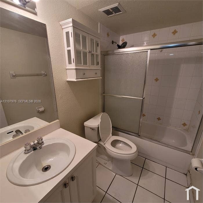 5100 SW 41st Street, #101, Hollywood, Hollywood, FL 33023 Bathroom featuring a vanity with an integrated basin, a wall-mounted glass-front cabinet, a shower-tub combination with sliding glass doors, and tiled flooring