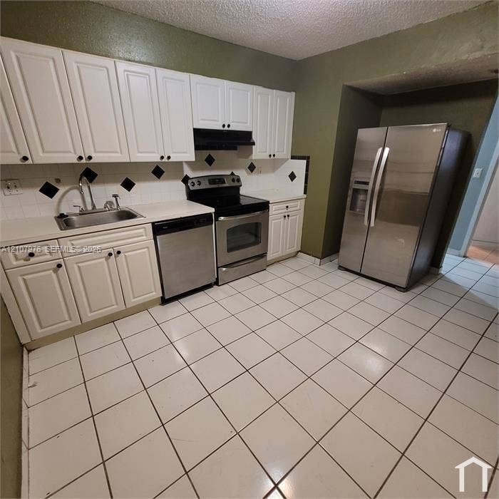 5100 SW 41st Street, #101, Hollywood, Hollywood, FL 33023 Kitchen featuring white shaker-style cabinetry, stainless steel appliances, ceramic tile flooring, and a decorative tile backsplash