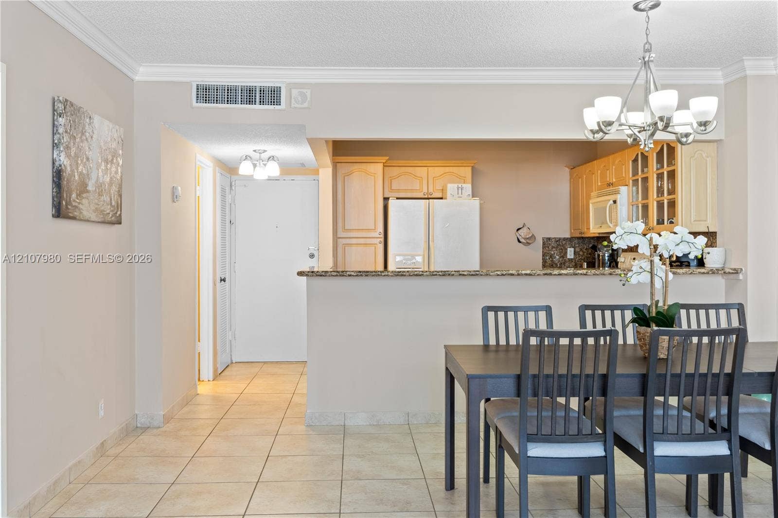 3725 S Ocean Drive, #1120, Hollywood, Hollywood, FL 33019 Kitchen featuring wood cabinetry, stone countertops, and a breakfast bar, complemented by tile flooring and a multi-light chandelier