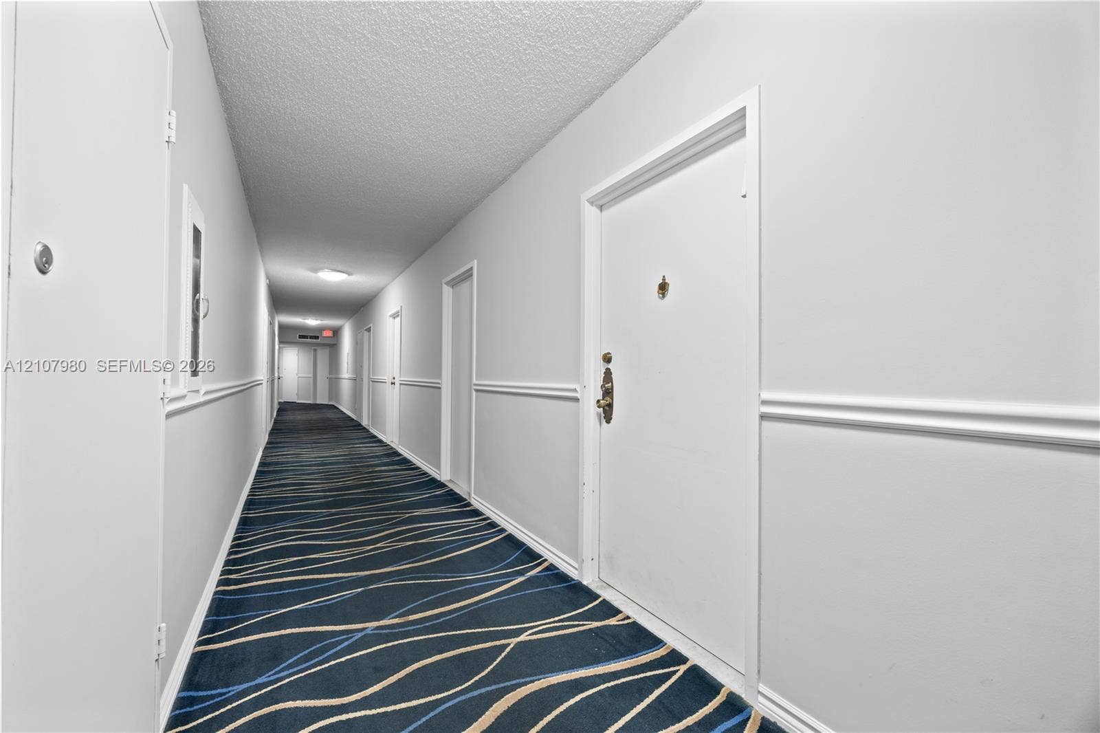 3725 S Ocean Drive, #1120, Hollywood, Hollywood, FL 33019 Interior hallway featuring patterned carpeting, white interior doors, and chair rail molding
