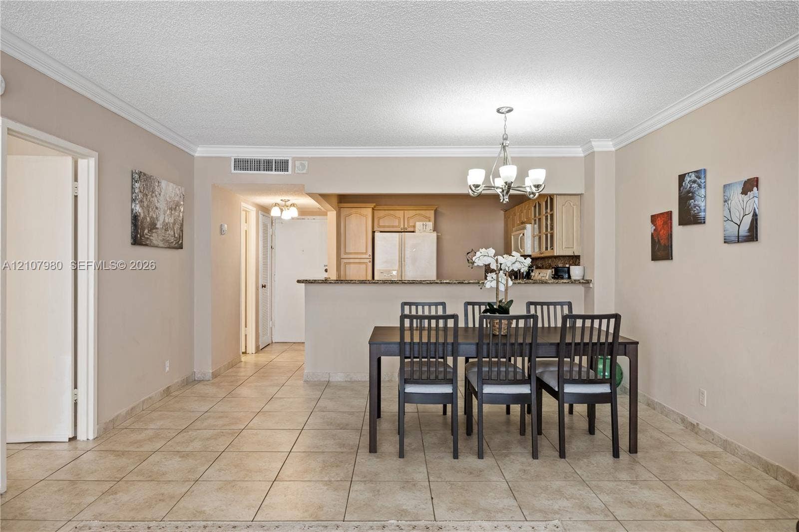 3725 S Ocean Drive, #1120, Hollywood, Hollywood, FL 33019 Ceramic tile flooring, crown molding, multi-arm chandelier, and a kitchen peninsula with stone-surface countertop
