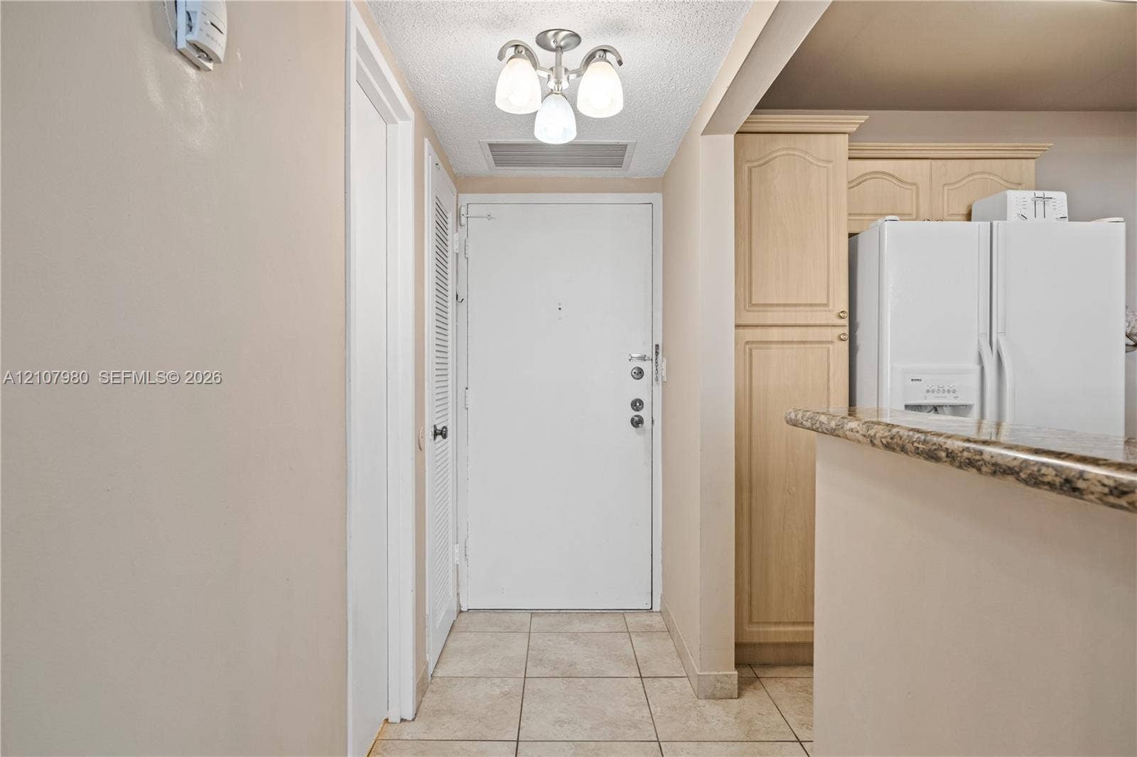 3725 S Ocean Drive, #1120, Hollywood, Hollywood, FL 33019 Entryway featuring tile flooring, a three-light semi-flush mount fixture, and built-in light-wood cabinetry with stone-finish countertops