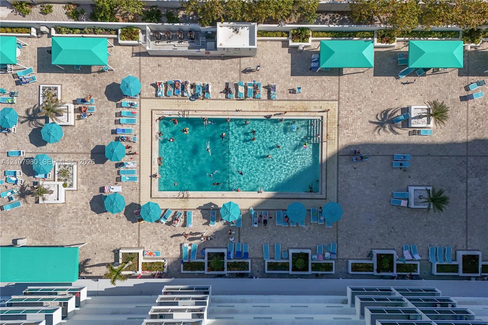 3725 S Ocean Drive, #1120, Hollywood, Hollywood, FL 33019 Rectangular swimming pool featuring tile surround, multiple built-in shade structures, paver decking, and integrated planters
