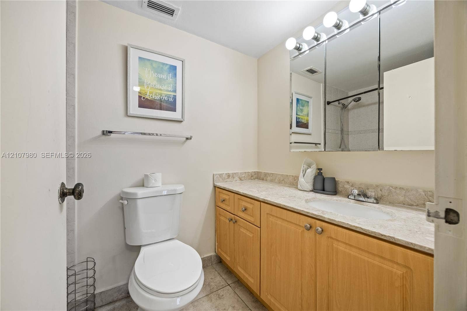 3725 S Ocean Drive, #1120, Hollywood, Hollywood, FL 33019 Full vanity with stone-finish countertop, integrated sink, three-door mirrored medicine cabinet, and wood-finish cabinetry