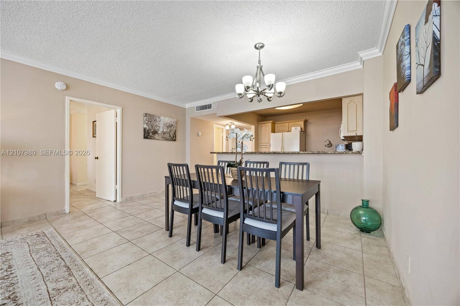 3725 S Ocean Drive, #1120, Hollywood, Hollywood, FL 33019 Dining area featuring neutral wall paint, tile flooring, crown molding, and an overhead multi-light chandelier
