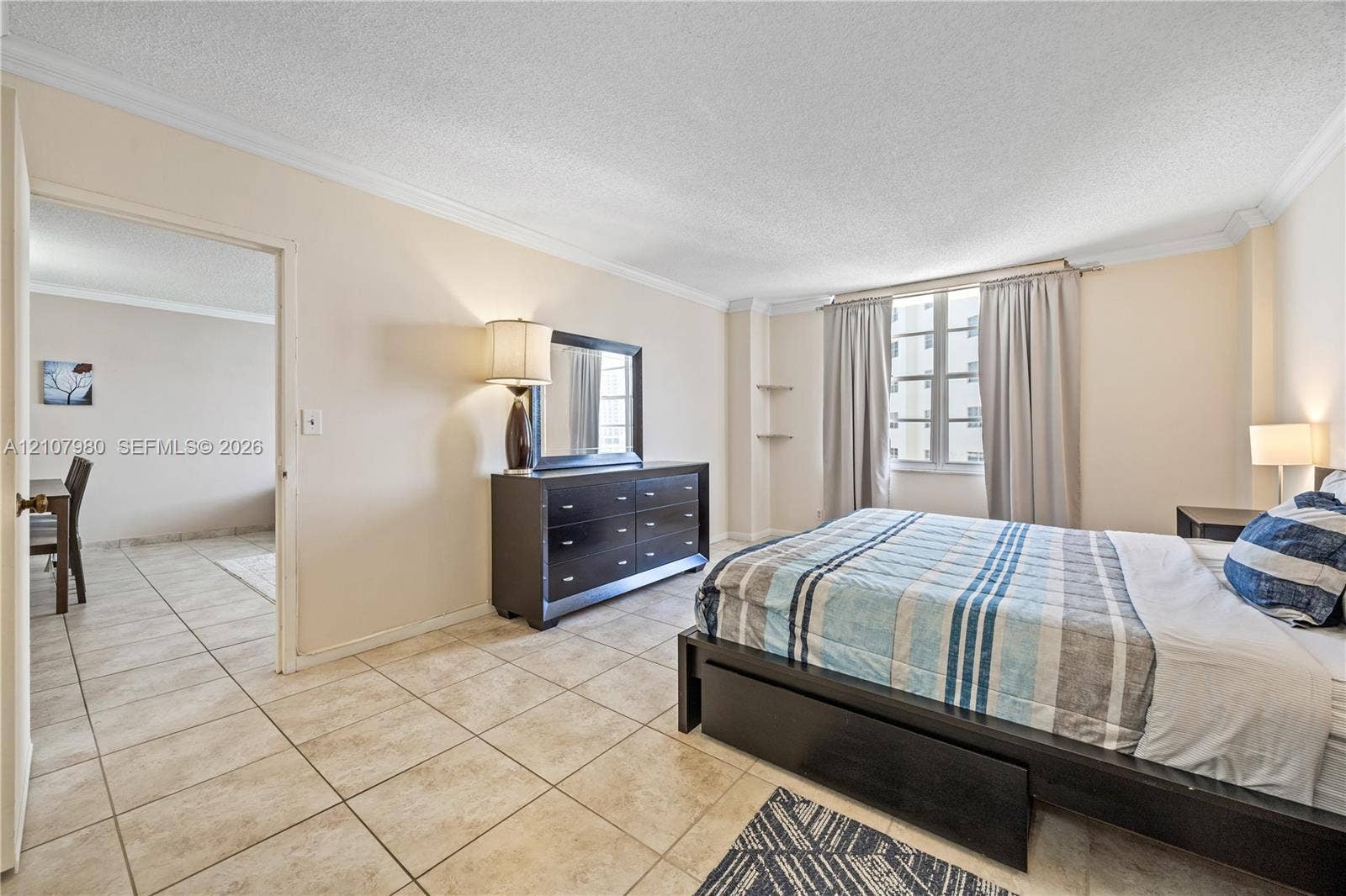 3725 S Ocean Drive, #1120, Hollywood, Hollywood, FL 33019 Neutral-toned interior featuring ceramic tile flooring, multi-pane window, ceiling crown molding, and built-in wall shelving