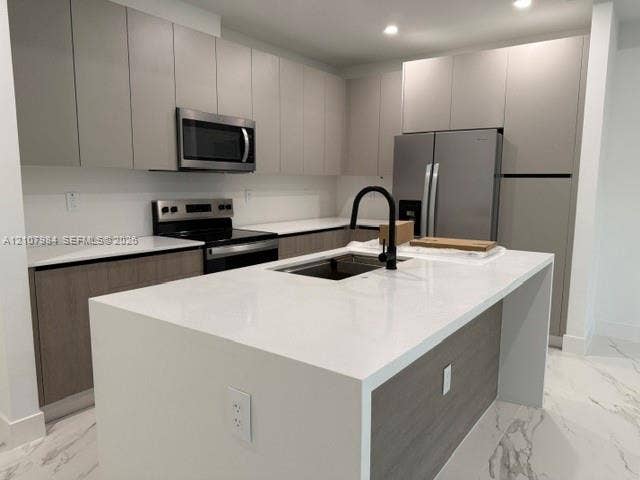 1567 NW 94th Way, #10, Coral Springs, Coral Springs, FL 33071 Kitchen featuring flat-panel cabinetry, a central island with a stone-finish countertop, stainless steel appliances, a matte black faucet, and large-format tile flooring