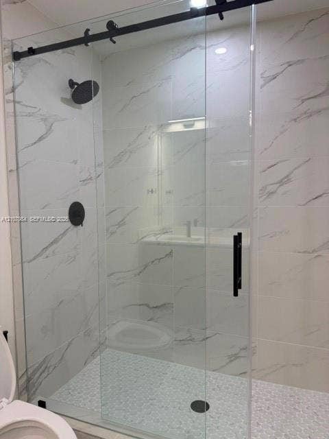 1567 NW 94th Way, #10, Coral Springs, Coral Springs, FL 33071 Walk-in shower featuring large-format stone-pattern tile, a glass sliding door with matte black hardware, a round rainfall showerhead, and a textured pebble tile floor