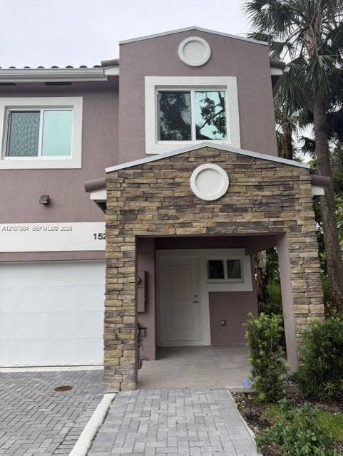 1567 NW 94th Way, #10, Coral Springs, Coral Springs, FL 33071 Multi-level exterior featuring a stone-veneer entryway, solid panel front door, herringbone-pattern paver driveway, and circular architectural accents