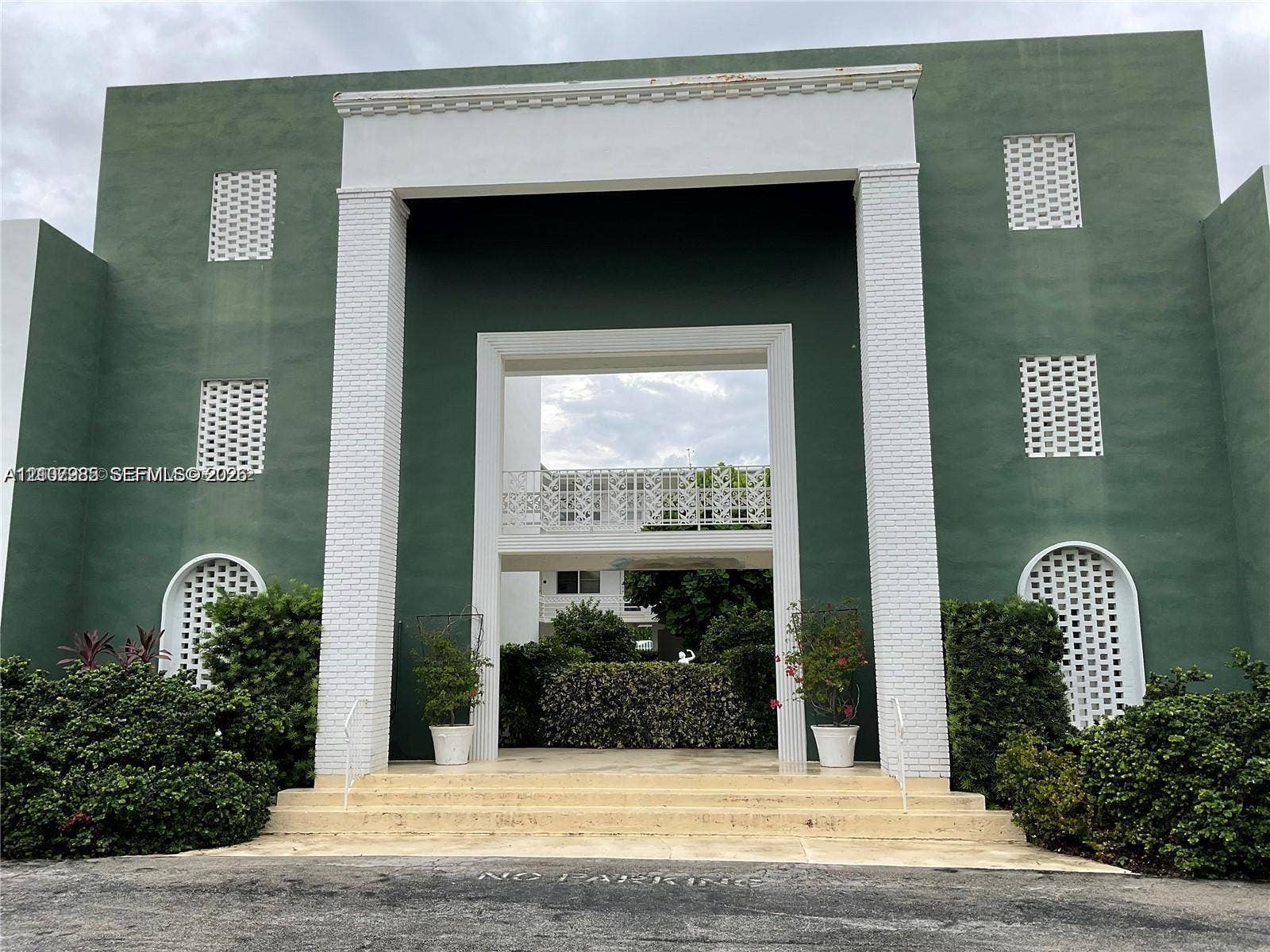 Exterior facade featuring a monumental entrance, prominent white brick columns, geometric lattice detailing, and arched accents