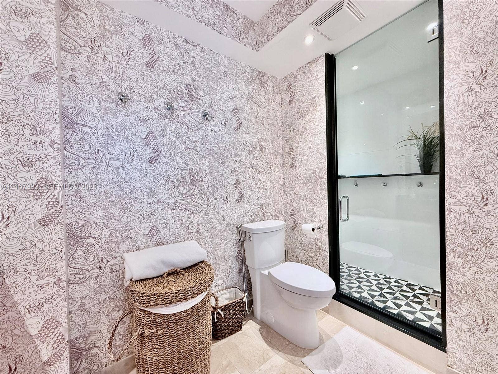10275 Collins Avenue, #1110, Bal Harbour, Bal Harbour, FL 33154 Patterned wall covering, floor-to-ceiling glass shower enclosure with matte black frame, geometric tile shower flooring, and two-piece toilet
