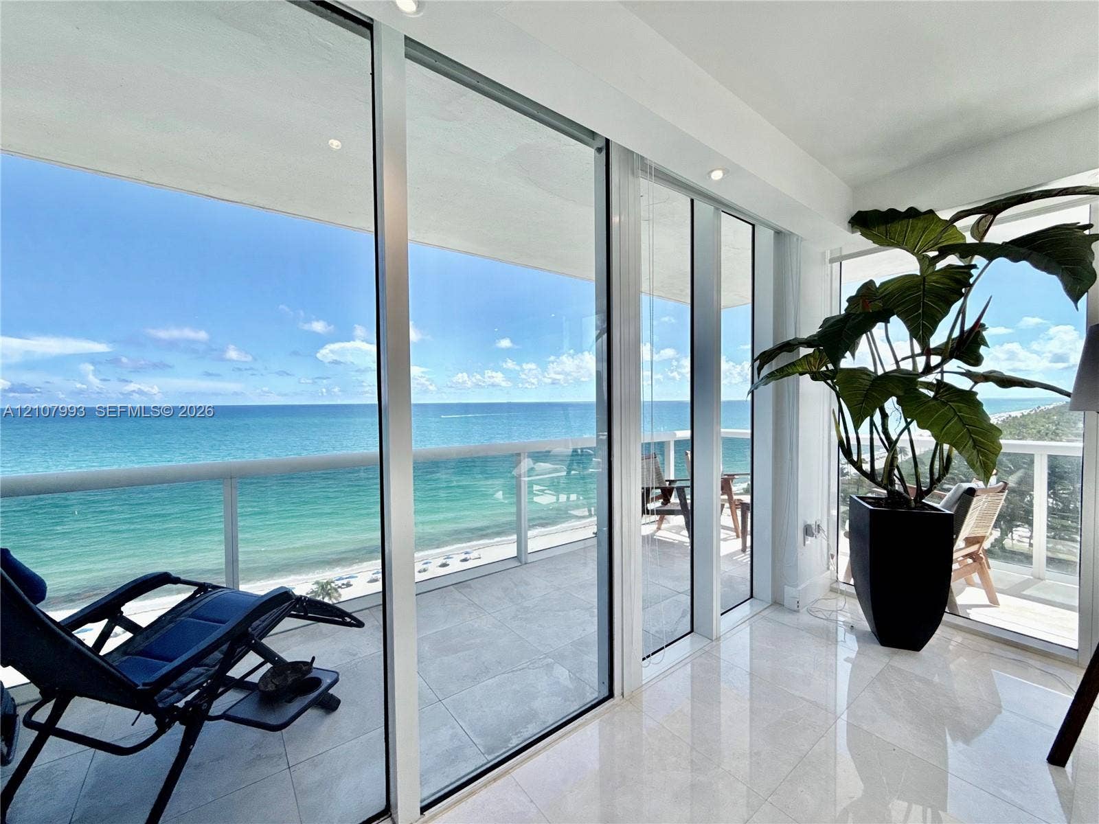 10275 Collins Avenue, #1110, Bal Harbour, Bal Harbour, FL 33154 Floor-to-ceiling glass sliding doors, large-format tile flooring, and a glass-paneled balcony overlooking the ocean