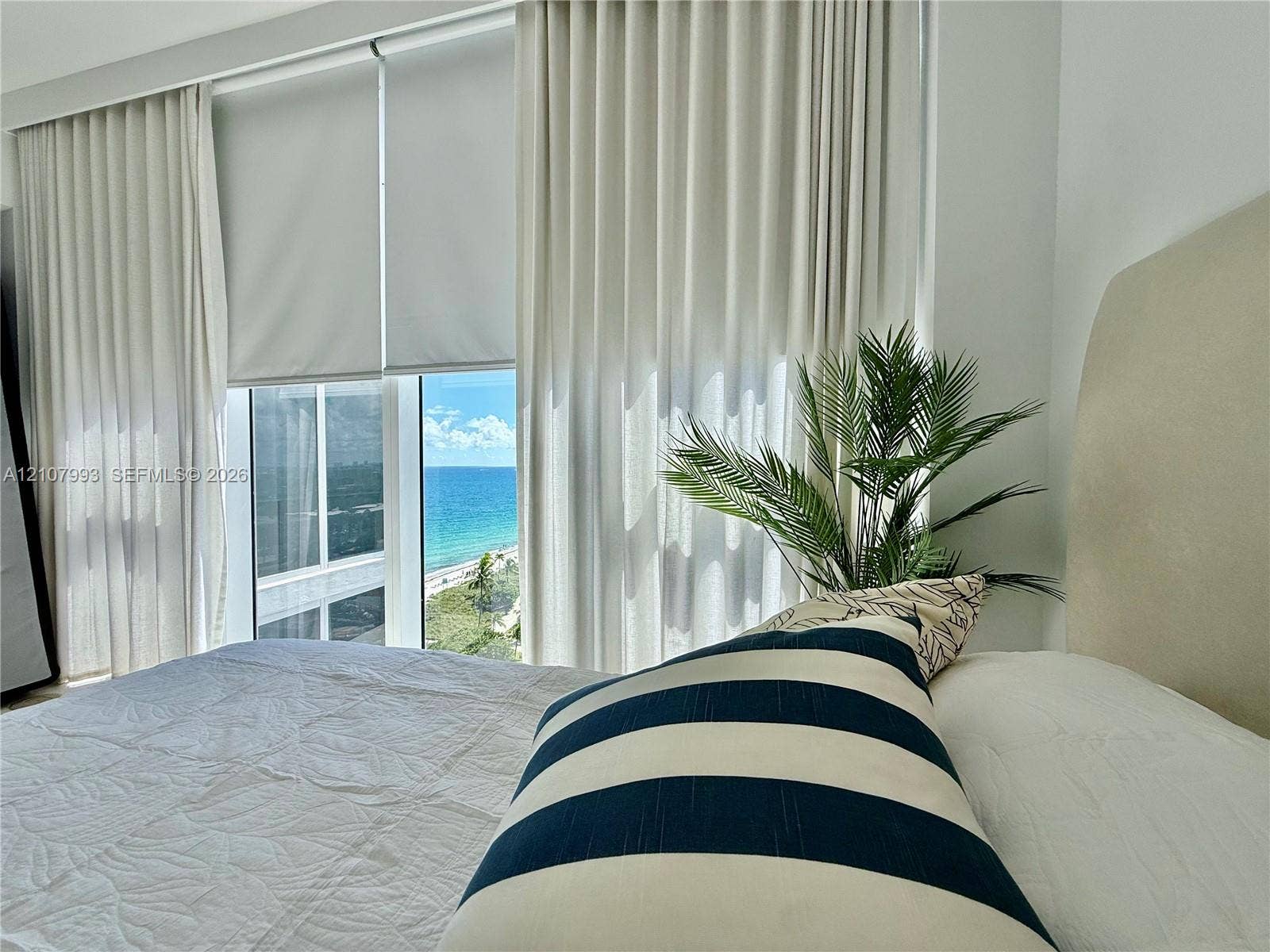 10275 Collins Avenue, #1110, Bal Harbour, Bal Harbour, FL 33154 Floor-to-ceiling windows featuring automated roller shades and neutral drapery, providing a horizon of the ocean and coastal shoreline