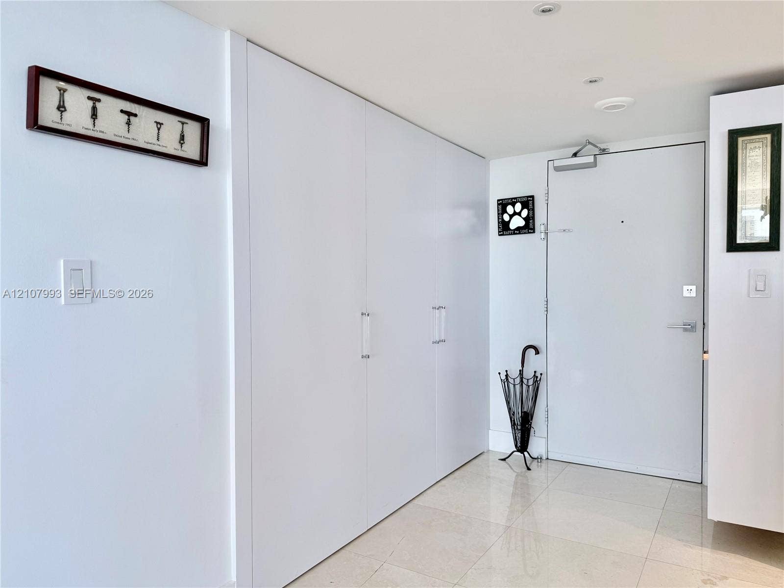 10275 Collins Avenue, #1110, Bal Harbour, Bal Harbour, FL 33154 Floor-to-ceiling built-in white cabinetry with chrome hardware, polished stone tile flooring, and solid-core metal entry door with overhead hydraulic closer