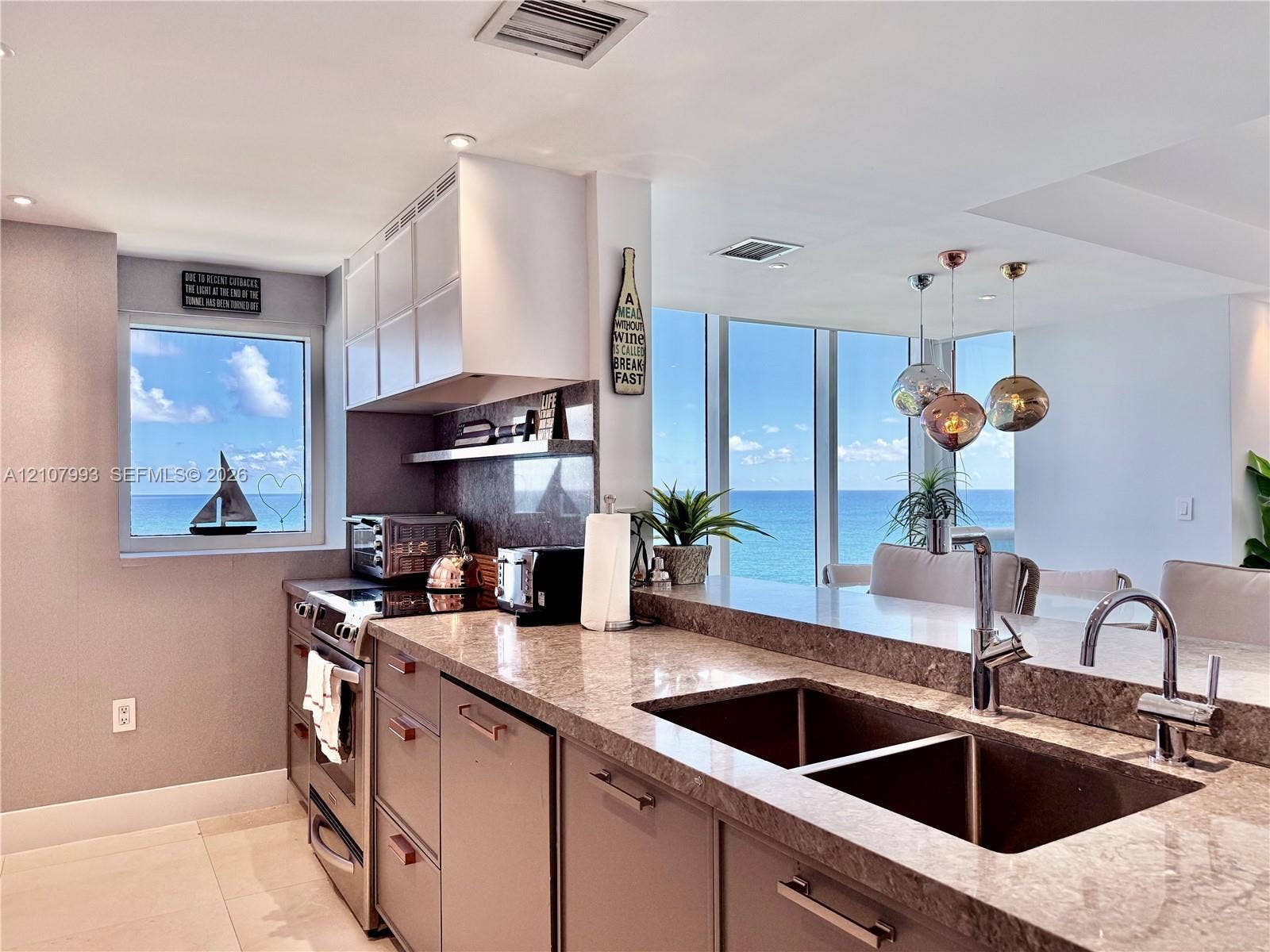 10275 Collins Avenue, #1110, Bal Harbour, Bal Harbour, FL 33154 Kitchen featuring flat-panel cabinetry, stone countertops, stainless steel appliances, double-basin undermount sink with high-arc faucet, and floor-to-ceiling windows with coastal scenery