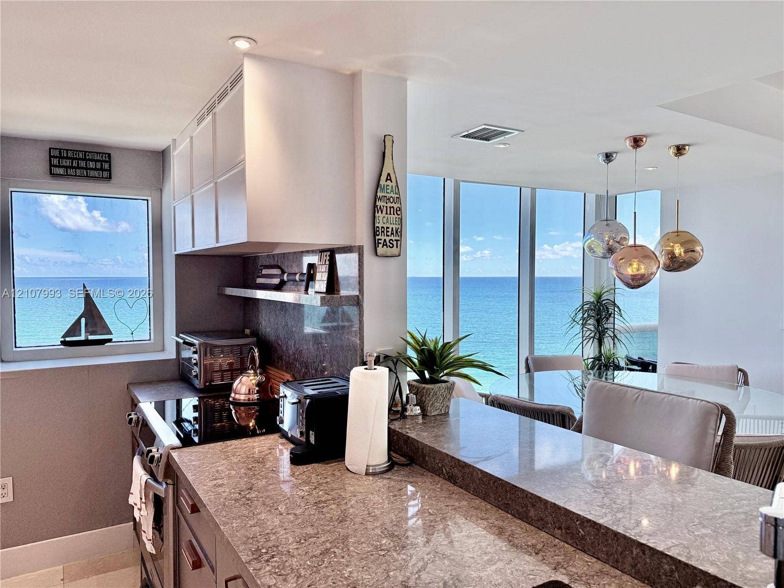10275 Collins Avenue, #1110, Bal Harbour, Bal Harbour, FL 33154 Kitchen featuring a stone-surface breakfast bar, slab backsplash, light-toned cabinetry, recessed lighting, and floor-to-ceiling windows with ocean scenery