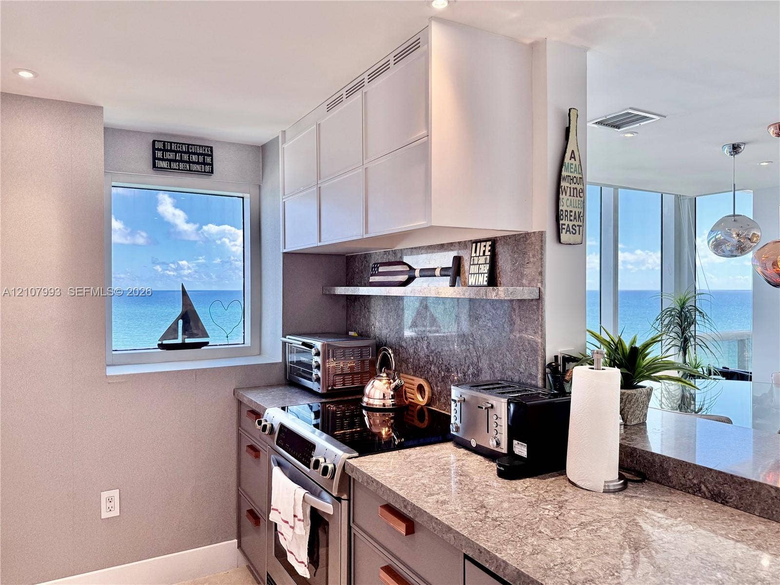 10275 Collins Avenue, #1110, Bal Harbour, Bal Harbour, FL 33154 Kitchen featuring white upper cabinetry, grey lower cabinetry, stone-finish countertops, stone-finish backsplash, and built-in stainless steel range