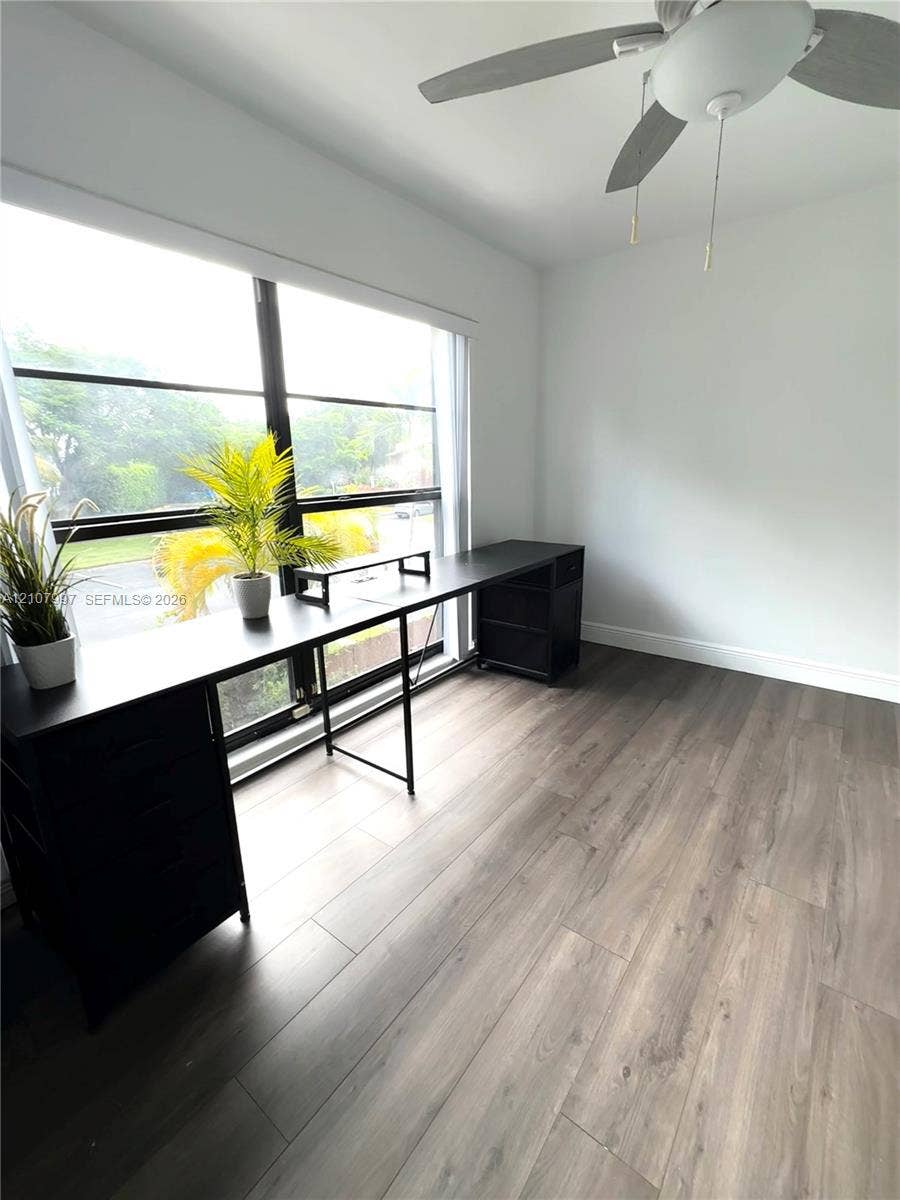 6814 SW 114th Place, #G65, Miami, FL 33173 Third bedroom Large floor-to-ceiling windows with dark framing, wood-finish flooring, and a ceiling fan with integrated lighting