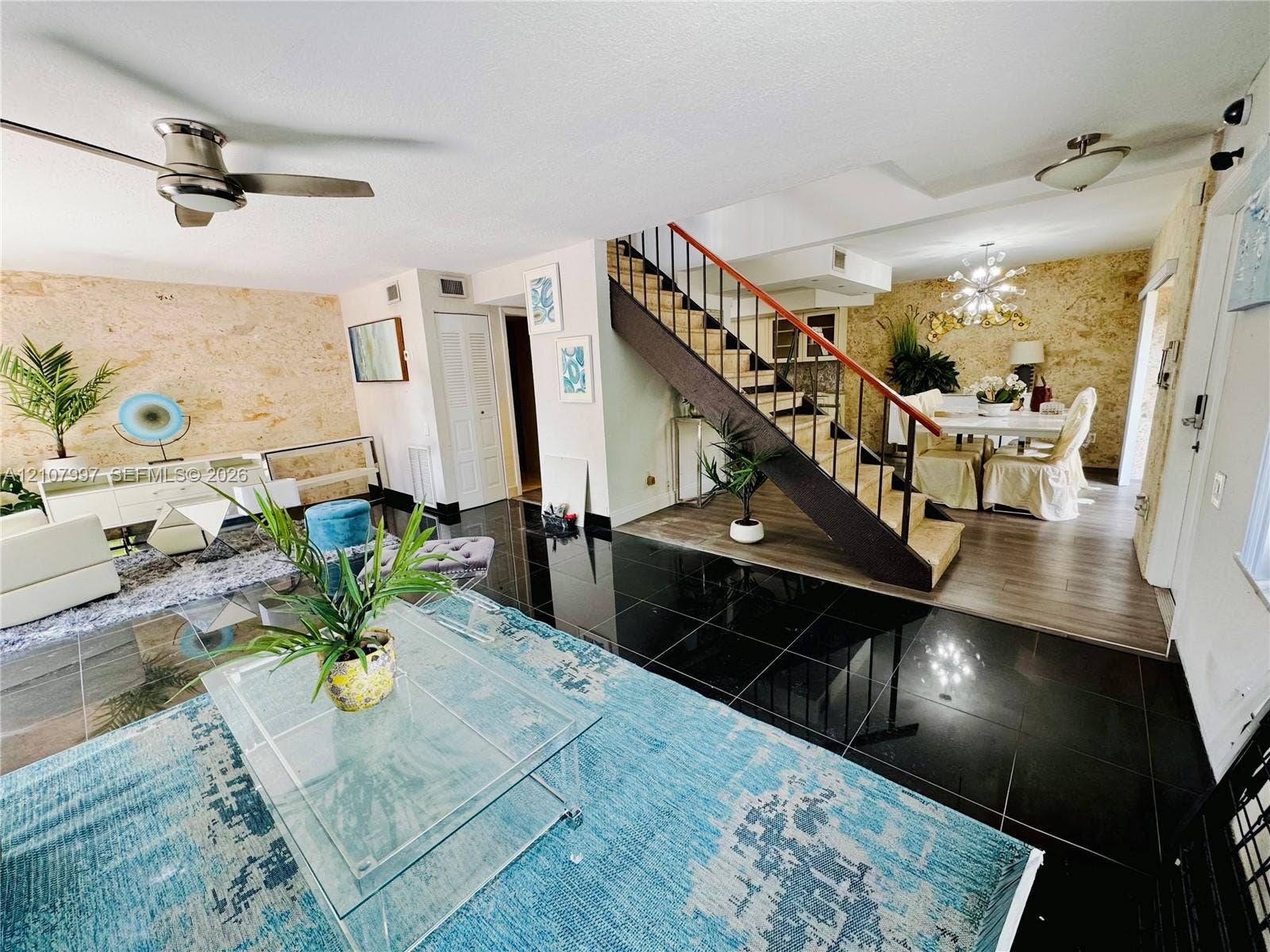 6814 SW 114th Place, #G65, Miami, FL 33173 Professional pictures coming soon! Open-concept interior featuring textured stone accent walls, high-gloss black tile flooring, and a staircase with wood beam & metal handrail