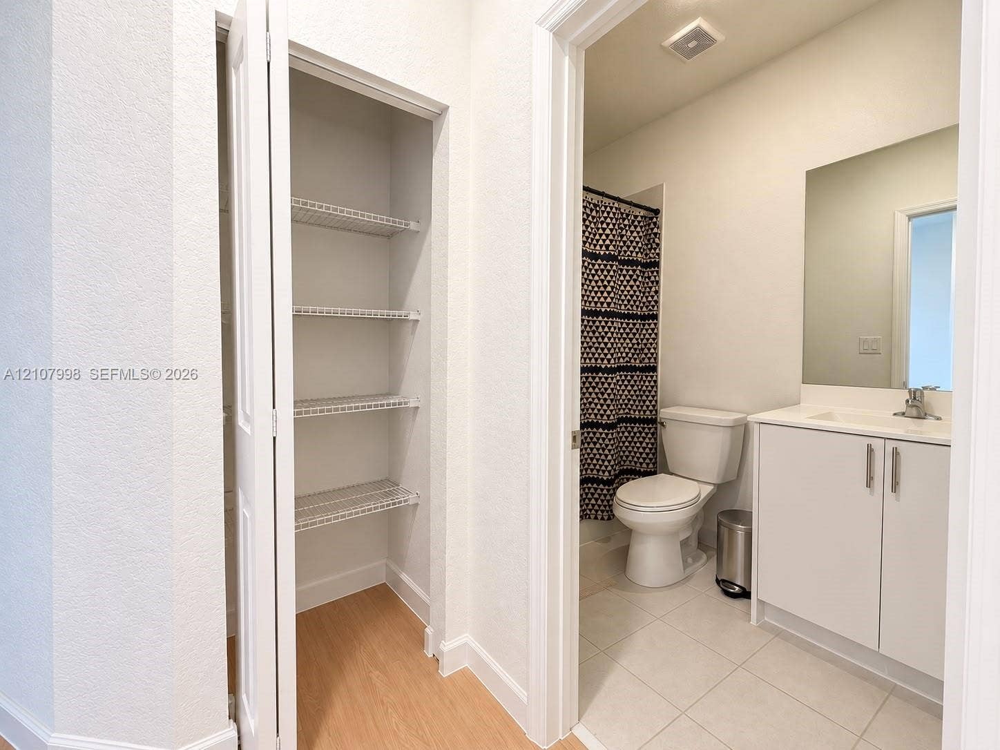 23471 SW 129th Avenue, Homestead, Homestead, FL 33032 Built-in closet with wire shelving, white vanity cabinet with integrated sink, rectangular frameless mirror, and neutral tile flooring
