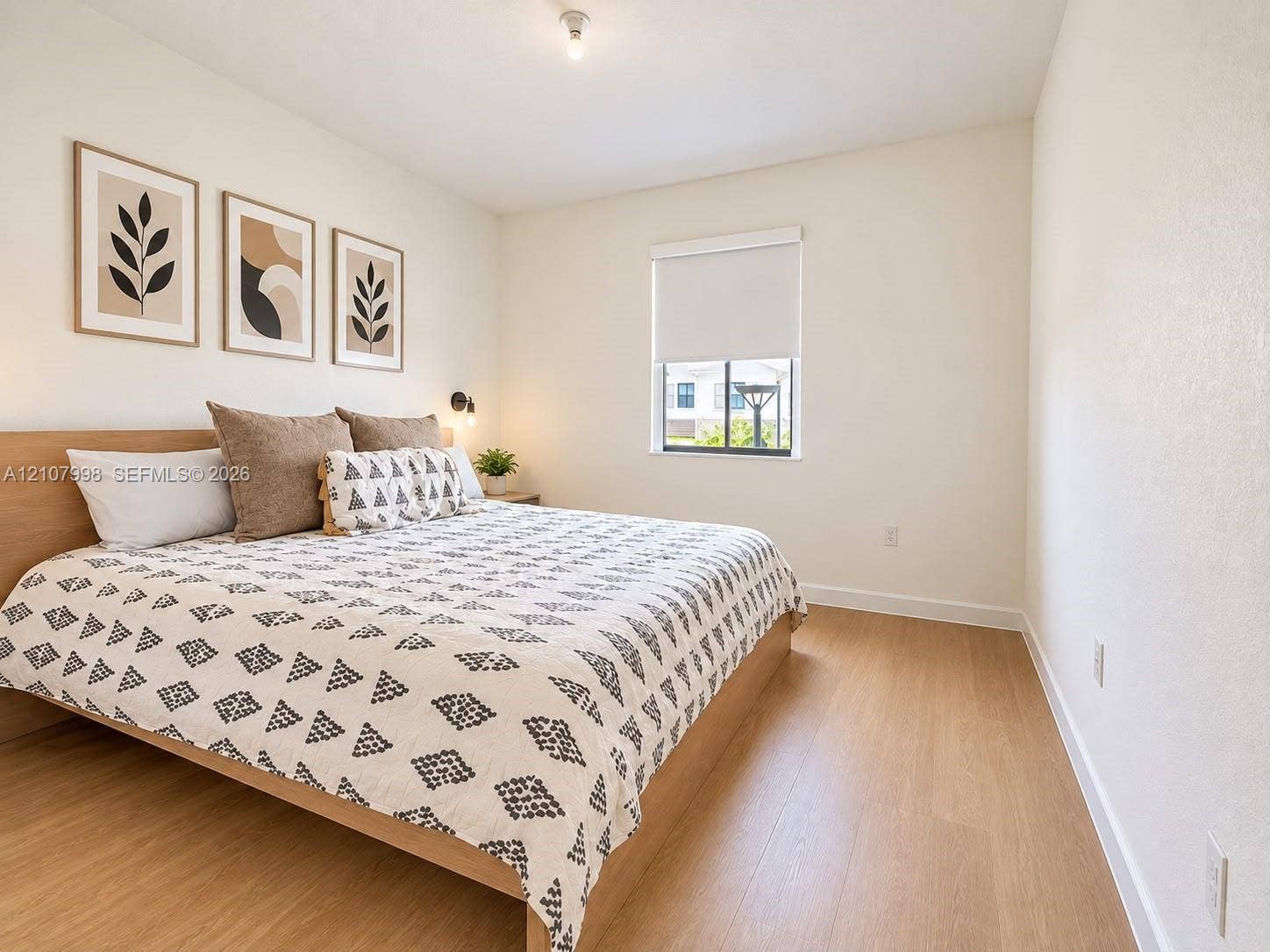 23471 SW 129th Avenue, Homestead, Homestead, FL 33032 Neutral-toned bedroom featuring wood-finish flooring, a single-pane window with a roller shade, and a built-in wall-mounted light fixture