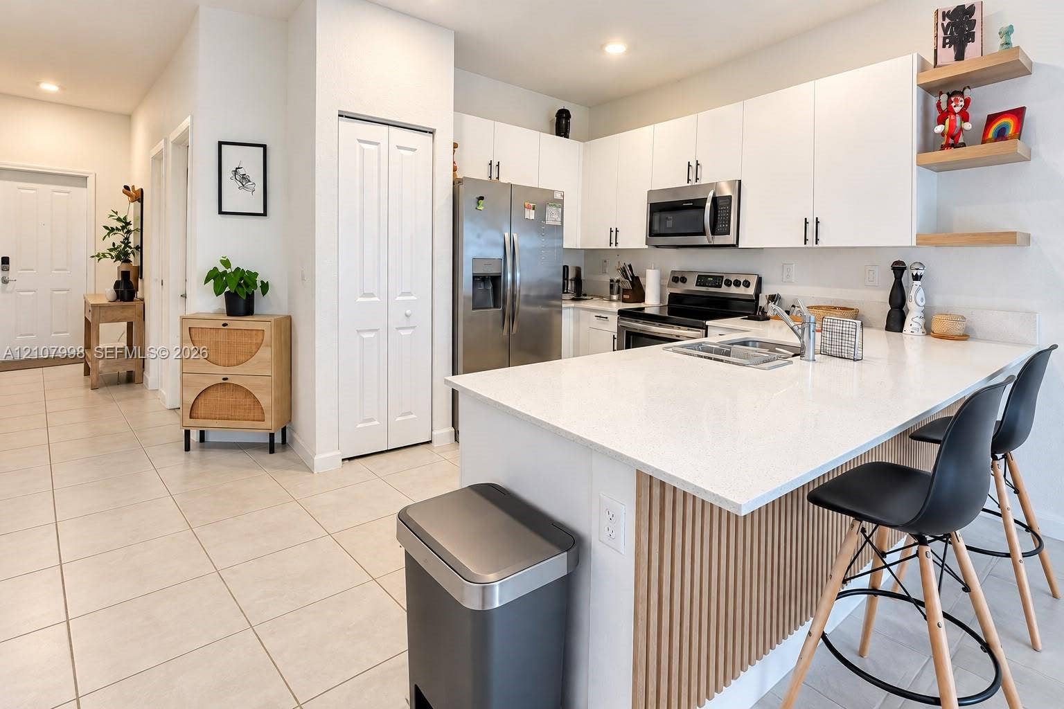 23471 SW 129th Avenue, Homestead, Homestead, FL 33032 Kitchen featuring white flat-panel cabinetry, a stone-finish island countertop, vertical wood-slat island detailing, stainless steel appliances, and floating shelves