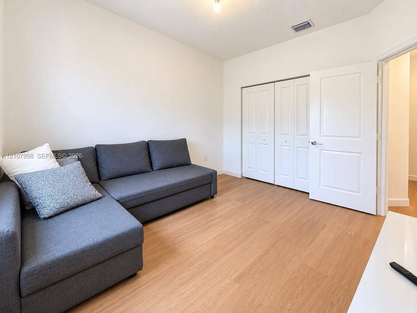23471 SW 129th Avenue, Homestead, Homestead, FL 33032 Interior room featuring wood-finish flooring, double-panel closet doors, and a solid-core interior door with satin nickel hardware