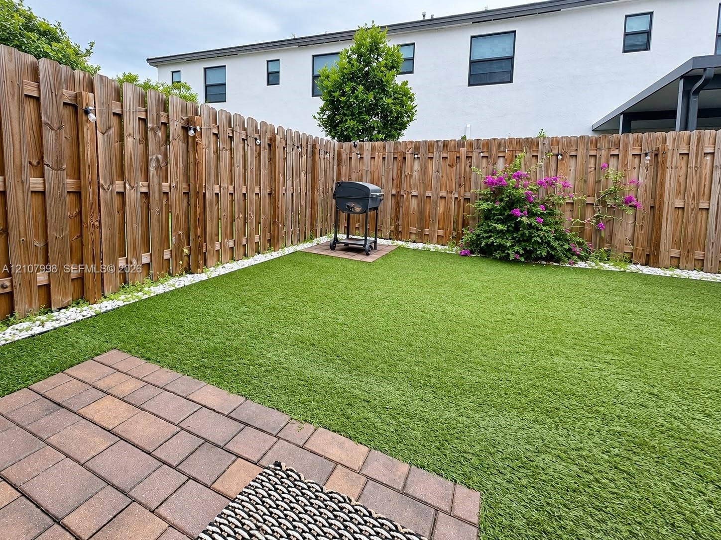 23471 SW 129th Avenue, Homestead, Homestead, FL 33032 Private backyard featuring synthetic turf, paver patio, stone border, and wood privacy fencing