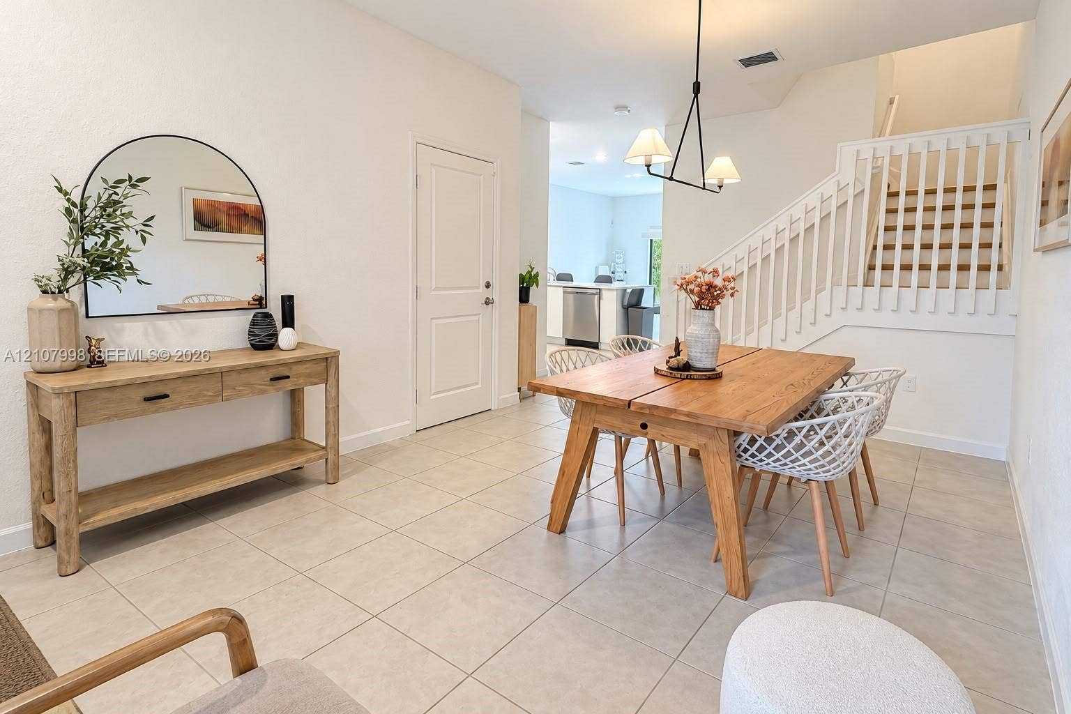 23471 SW 129th Avenue, Homestead, Homestead, FL 33032 Neutral tile flooring, staircase with white wooden balusters and wood-tread steps, contemporary dual-light pendant fixture, and white interior doors