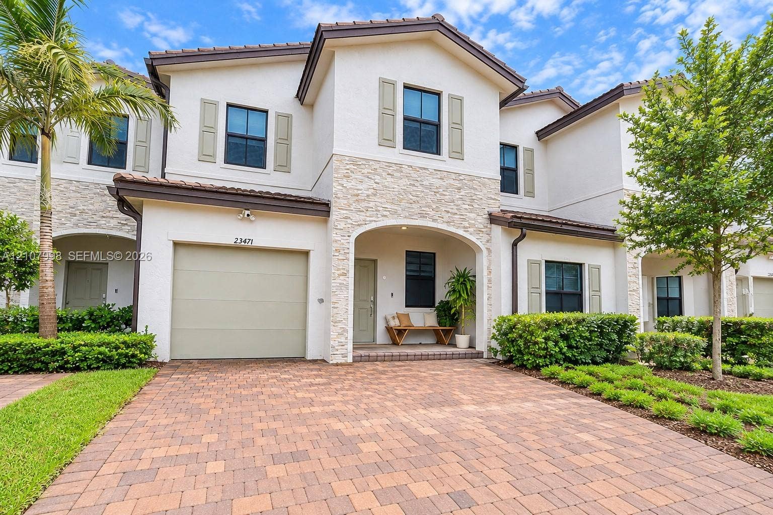 23471 SW 129th Avenue, Homestead, Homestead, FL 33032 Two-story exterior featuring light-toned stucco, decorative stone veneer accents, a paver driveway, an arched covered entryway, and shutter-framed windows